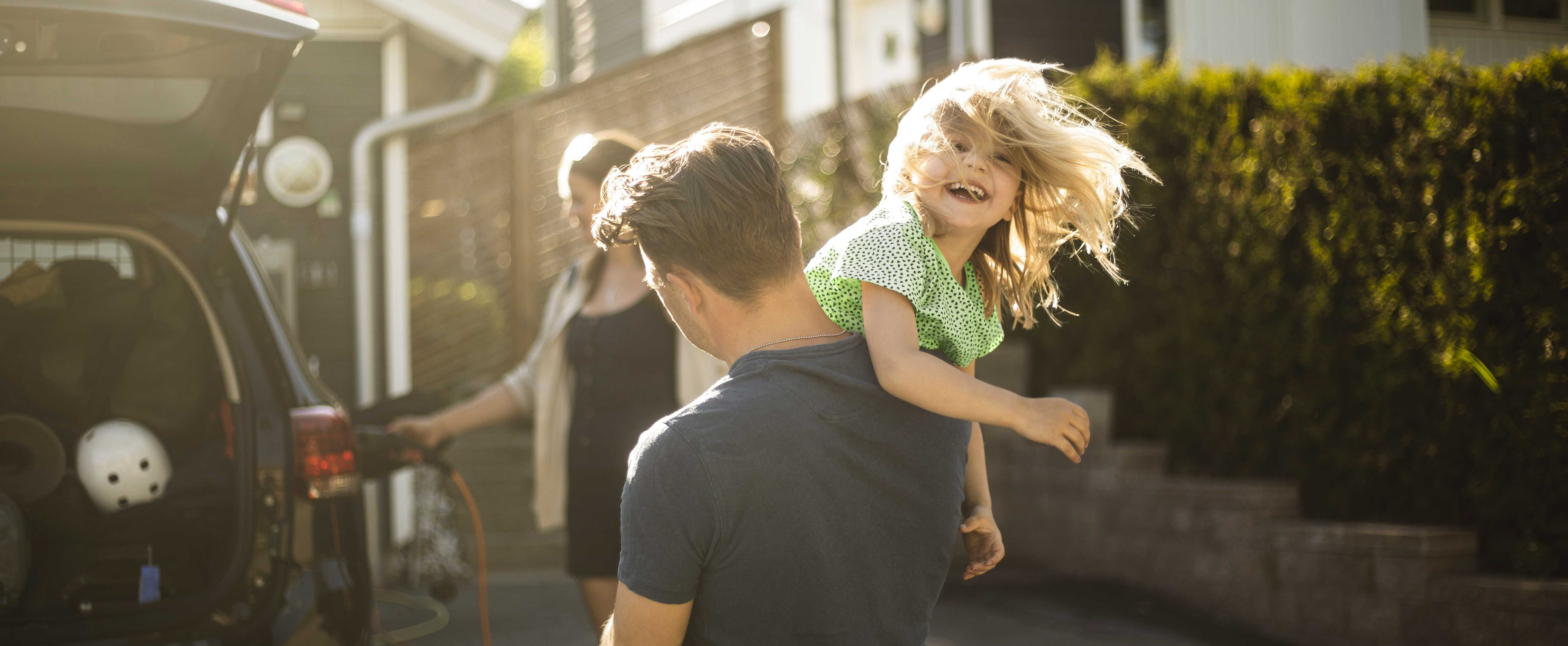 Dreiköpfige Familie lädt E-Auto.